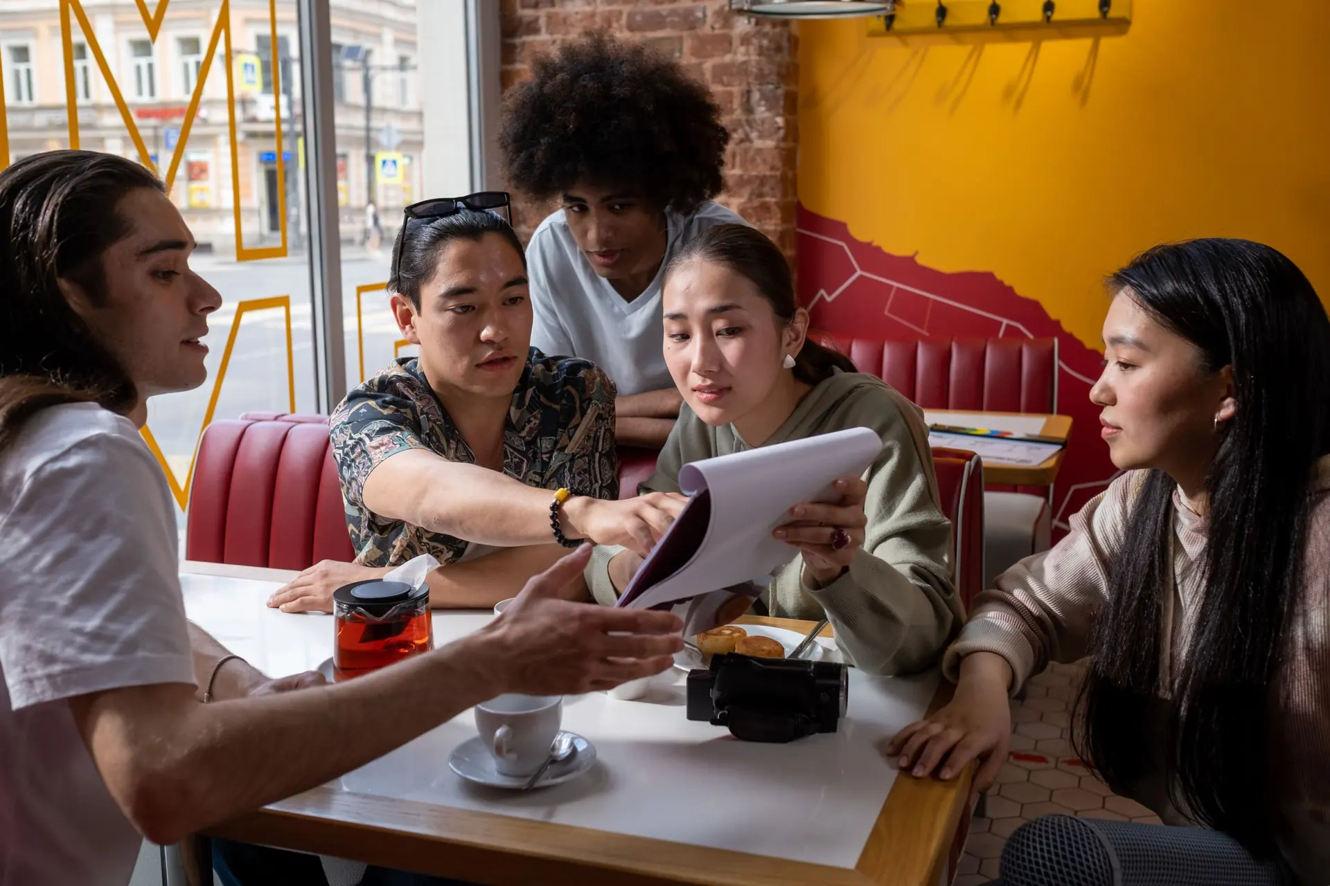 A group of international students working through a document together at a café table